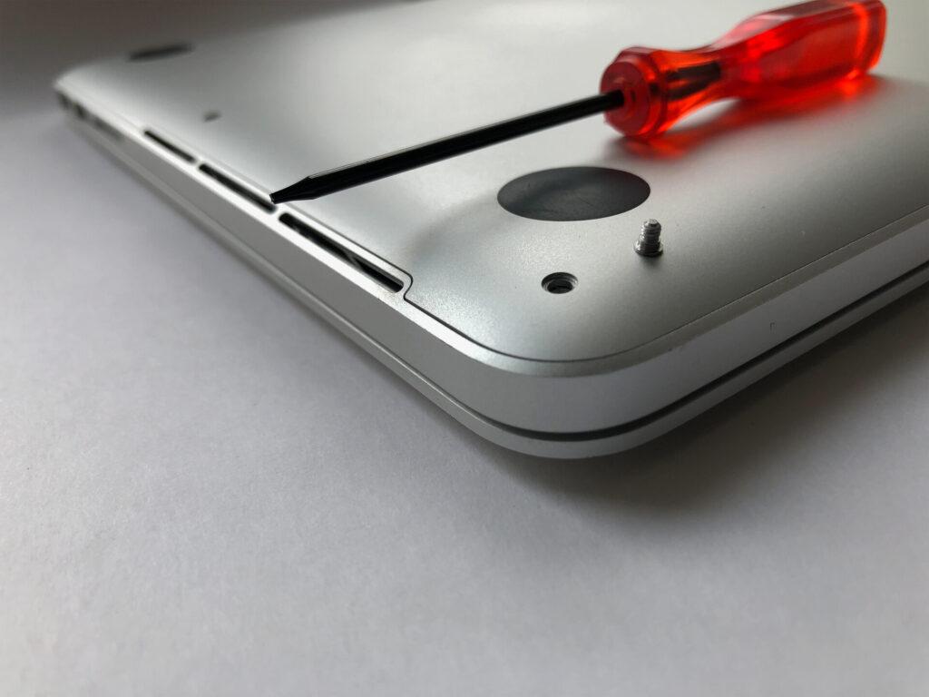 Rückseite des silbernen MacBook Pro 13 mit einem roten Schraubendreher
